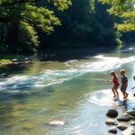 Niños jugando en el río entre árboles frondosos.