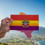 Mapa de Bolivia con su bandera sobre paisaje montañoso.