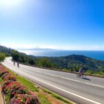 Sendero costero con ciclistas y paisaje marino.