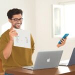 Hombre feliz usando móvil y computadora portátil