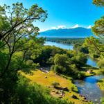 Paisaje verde con río y montañas al fondo.