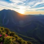 Amanecer sobre volcán y montañas verdes.