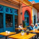 Personas conversando en terraza de café colorido.